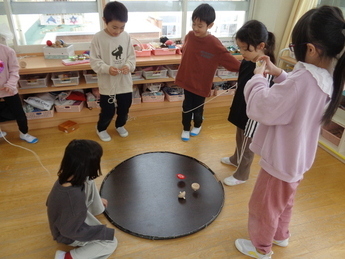 写真：友達と一緒に紐ごま回しをして遊んでいるところ