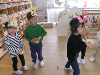 写真：鬼の面の頭につけ、新聞紙の豆をまいて遊んでいる様子