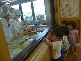 子ども達が給食室をのぞき、食材を見せてもらっている場面