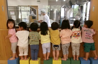 給食室の様子をのぞき込む子供たちの姿