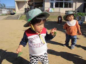 園庭でイチョウの葉をもって遊ぶ子ども達