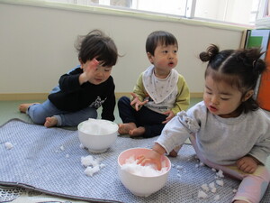 ボウルに入った雪に触れてみる子ども達