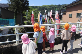 川にこいのぼりが泳いでいるところを見ている子ども達